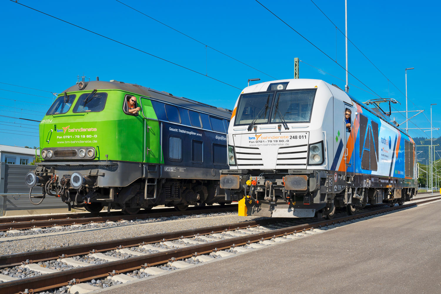 Zwei Züge, die nebeneinander auf Gleisen stehen und einen letzte Meile Transport durchführen werden.